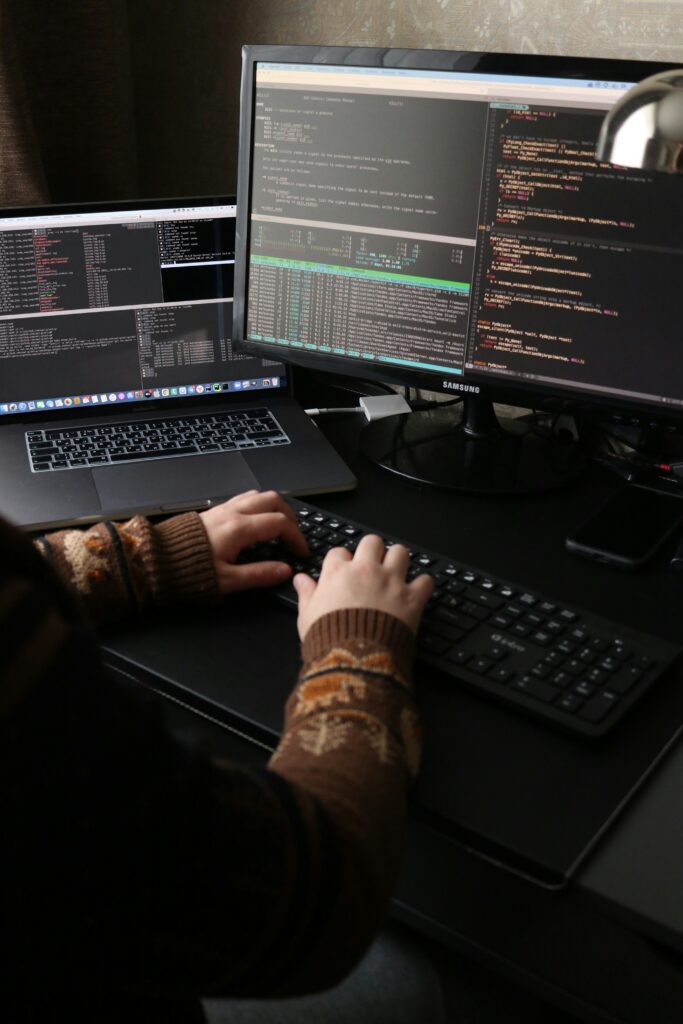 A penetration tester tries to hack a computer system, siting in front of several monitors of code